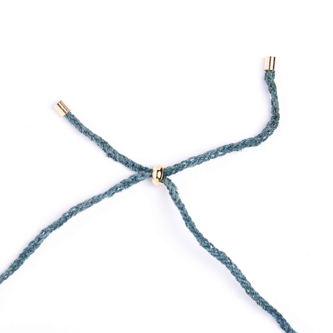 Close-up of a blue braided cord with gold metal clasps on a white background
