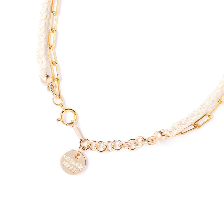 Gold bracelet with a round charm on a white background