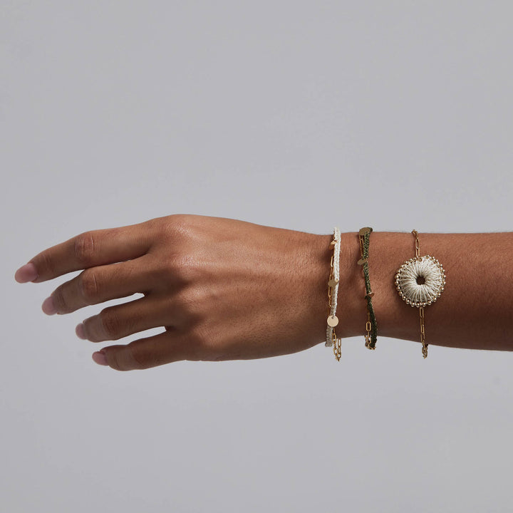 Hand wearing multiple bracelets on a gray background