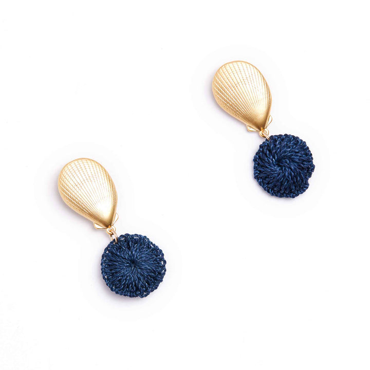 Pair of earrings with gold teardrop tops and navy pom-pom bottoms on a white background