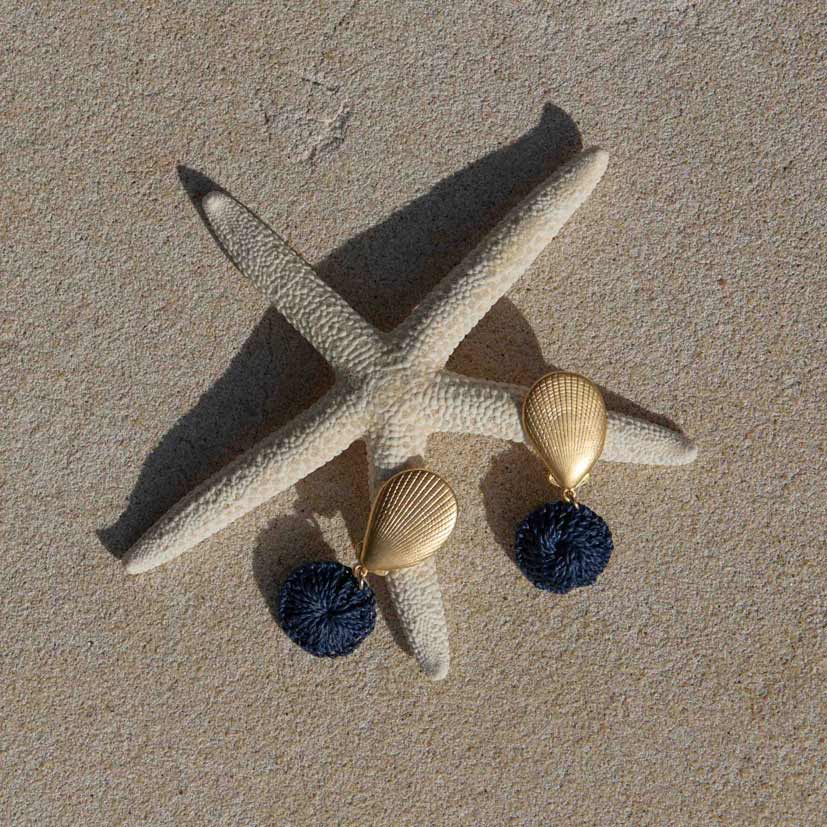 Starfish with two earrings on a sandy surface