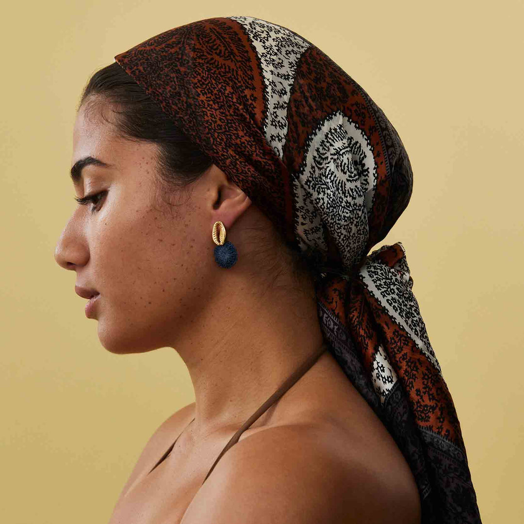 Woman wearing a patterned headscarf on a beige background