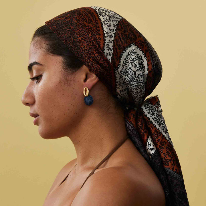 Woman wearing a patterned headscarf on a beige background