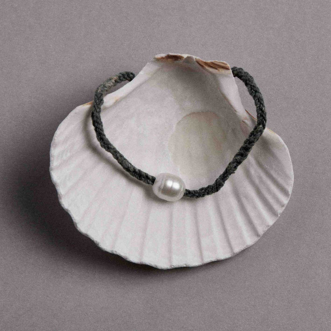 Pearl necklace on a seashell against a gray background