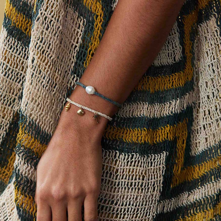Person wearing a bracelet with a textured garment in the background
