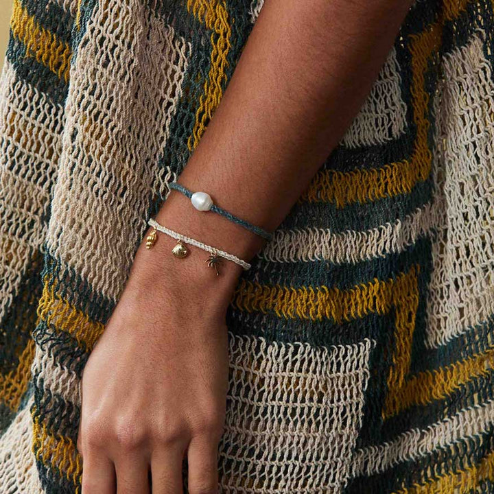 Person wearing a bracelet with a textured garment in the background