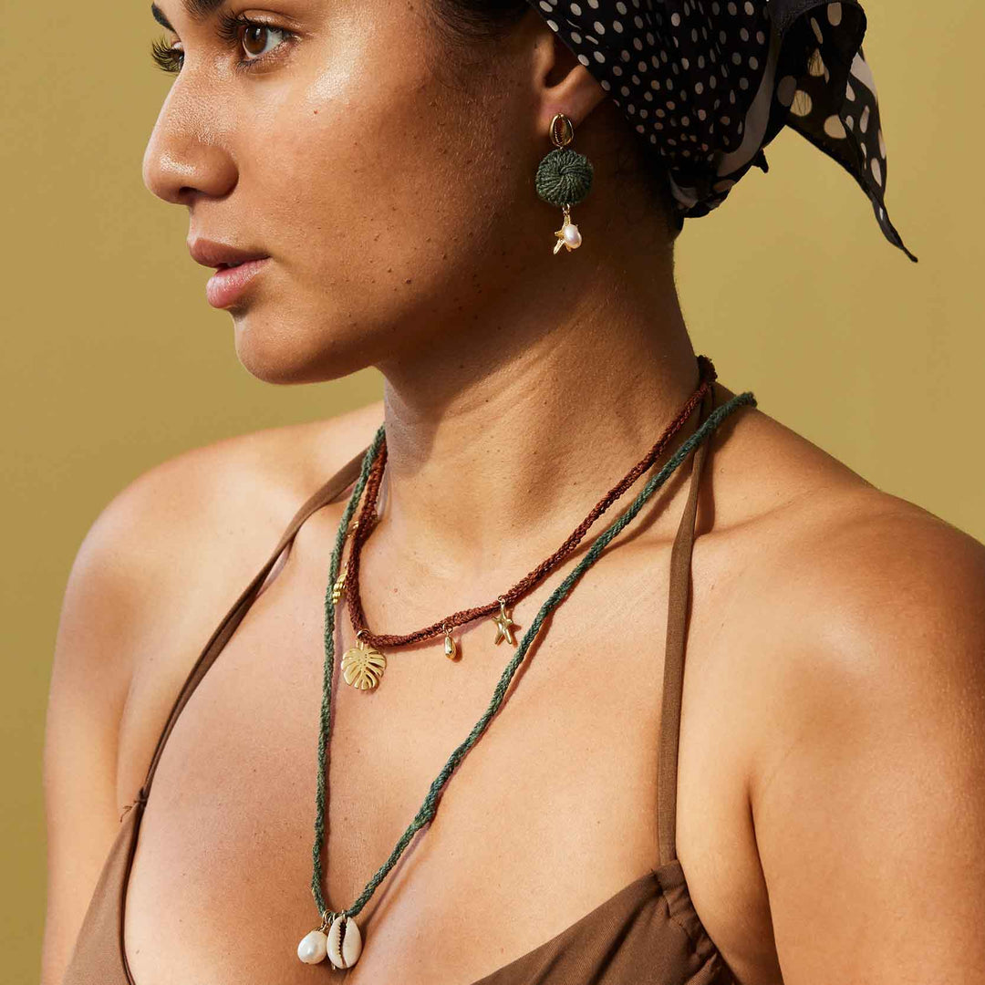 Woman wearing a headscarf and necklaces with a neutral background