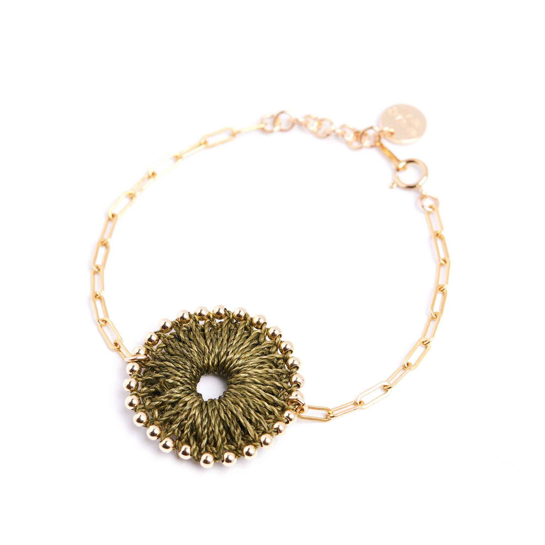 Bracelet with gold chain and textured green circular charm on a white background