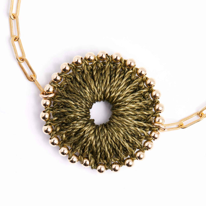 Necklace with a gold chain and green circular pendant on a white background