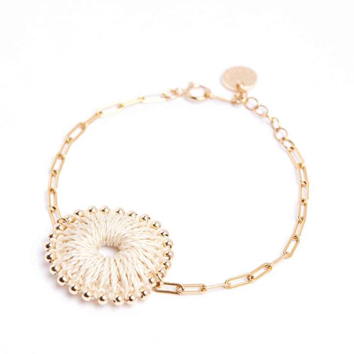 Gold bracelet with a decorative circular charm on a white background