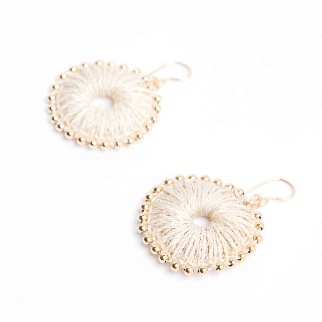 Pair of beige circular earrings with gold accents on a white background