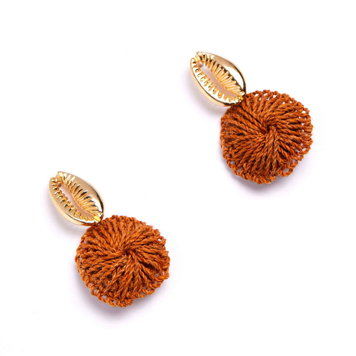 Pair of earrings with gold shell accents and rust-colored spherical poms on a white background