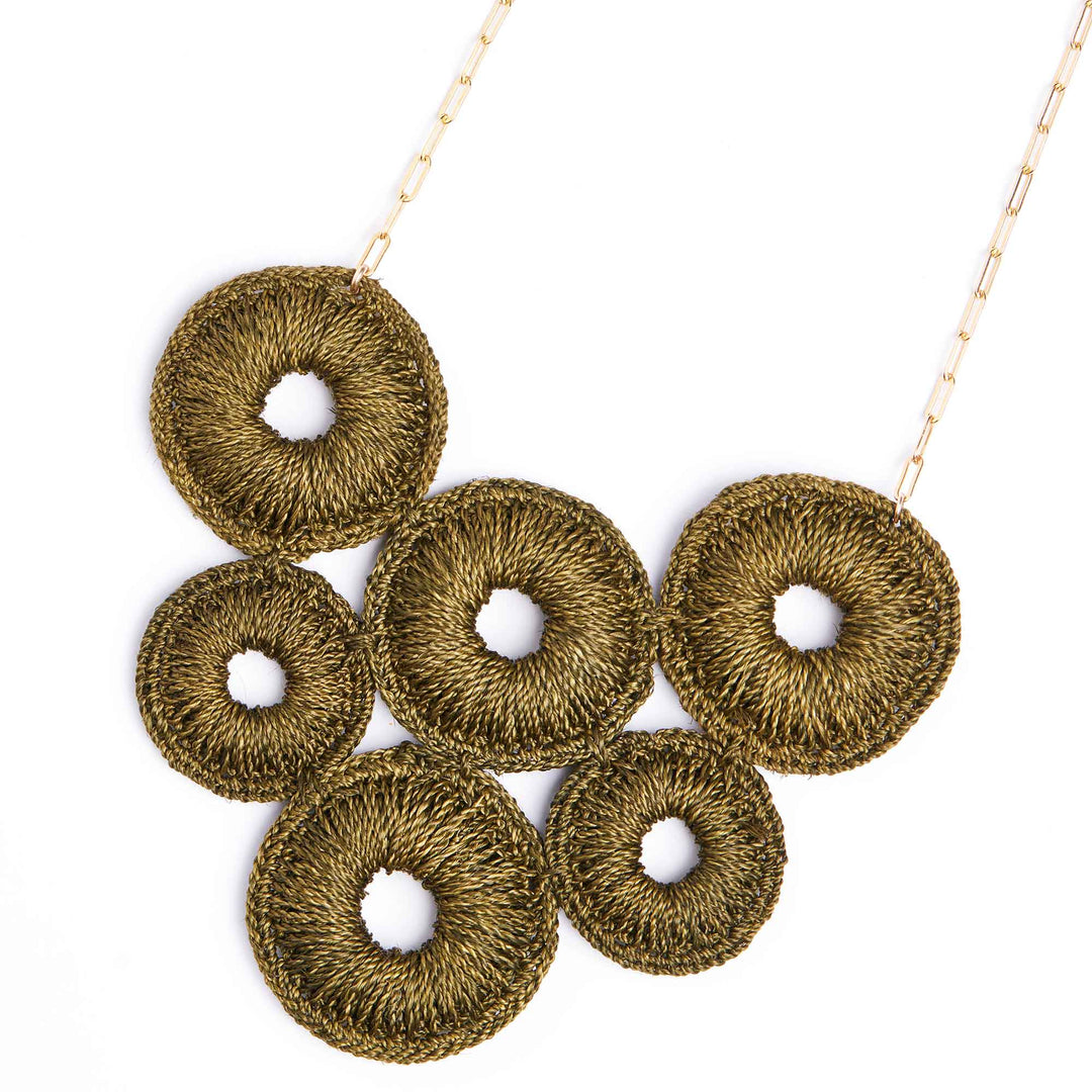 Gold necklace with circular pendant on a white background