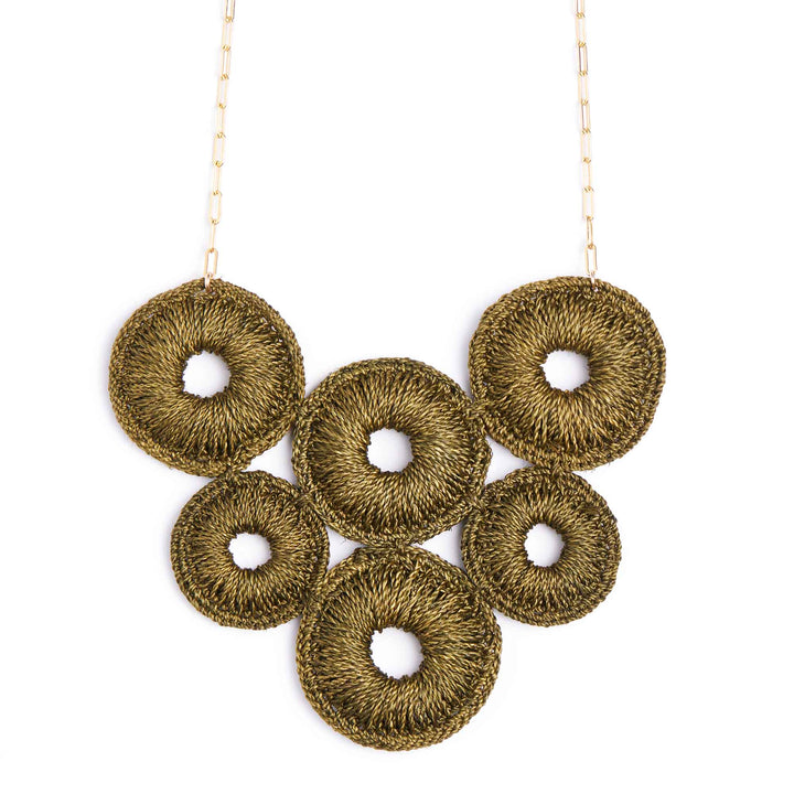 Gold necklace with circular pendant on a white background