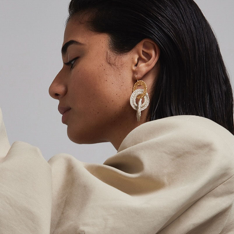 Woman wearing a gold and diamond earring against a neutral background