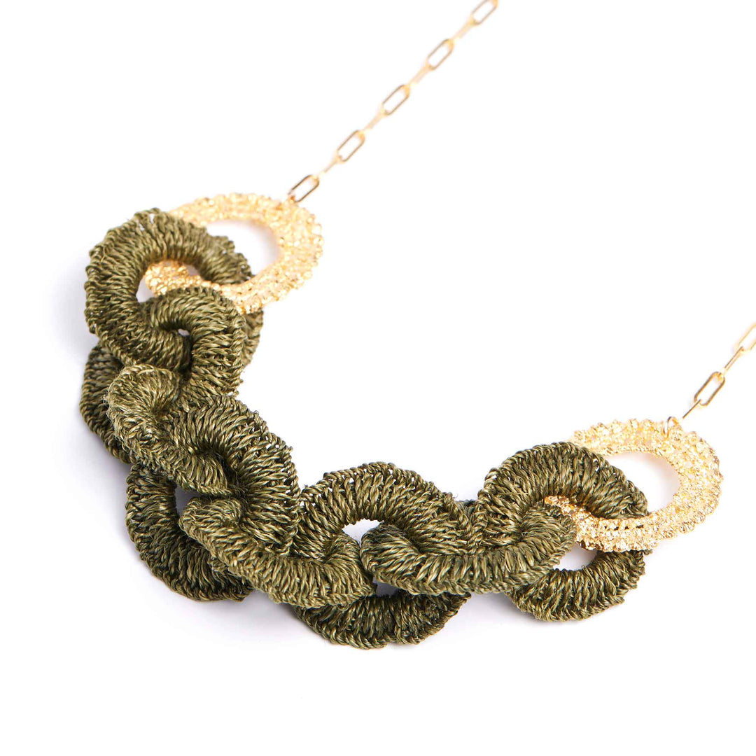 Green knotted necklace with gold accents on a white background