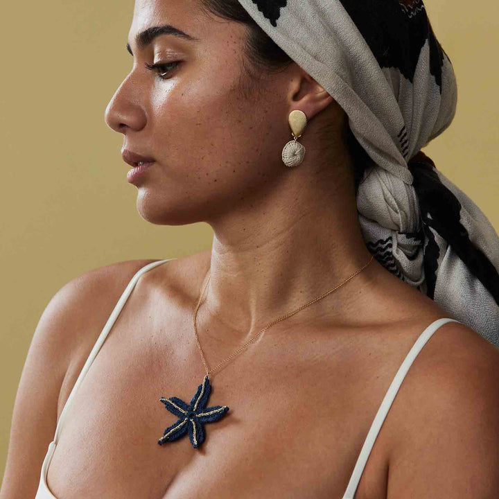 Woman wearing a starfish pendant necklace with a neutral background