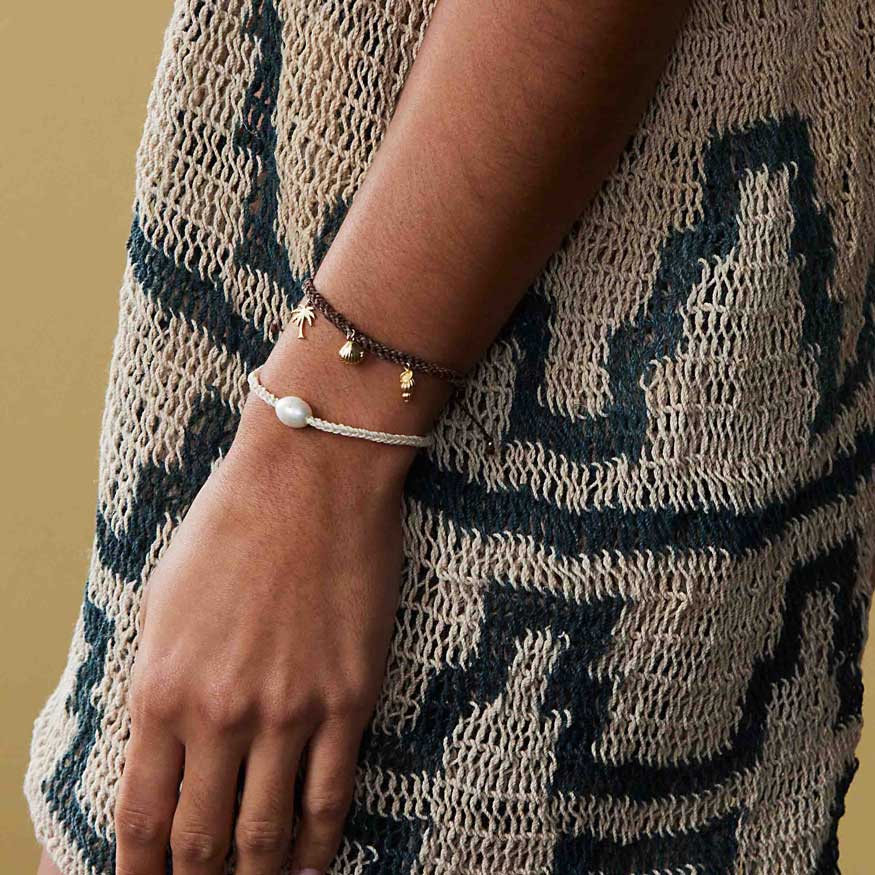 Person wearing a bracelet with a small bell on a patterned garment.