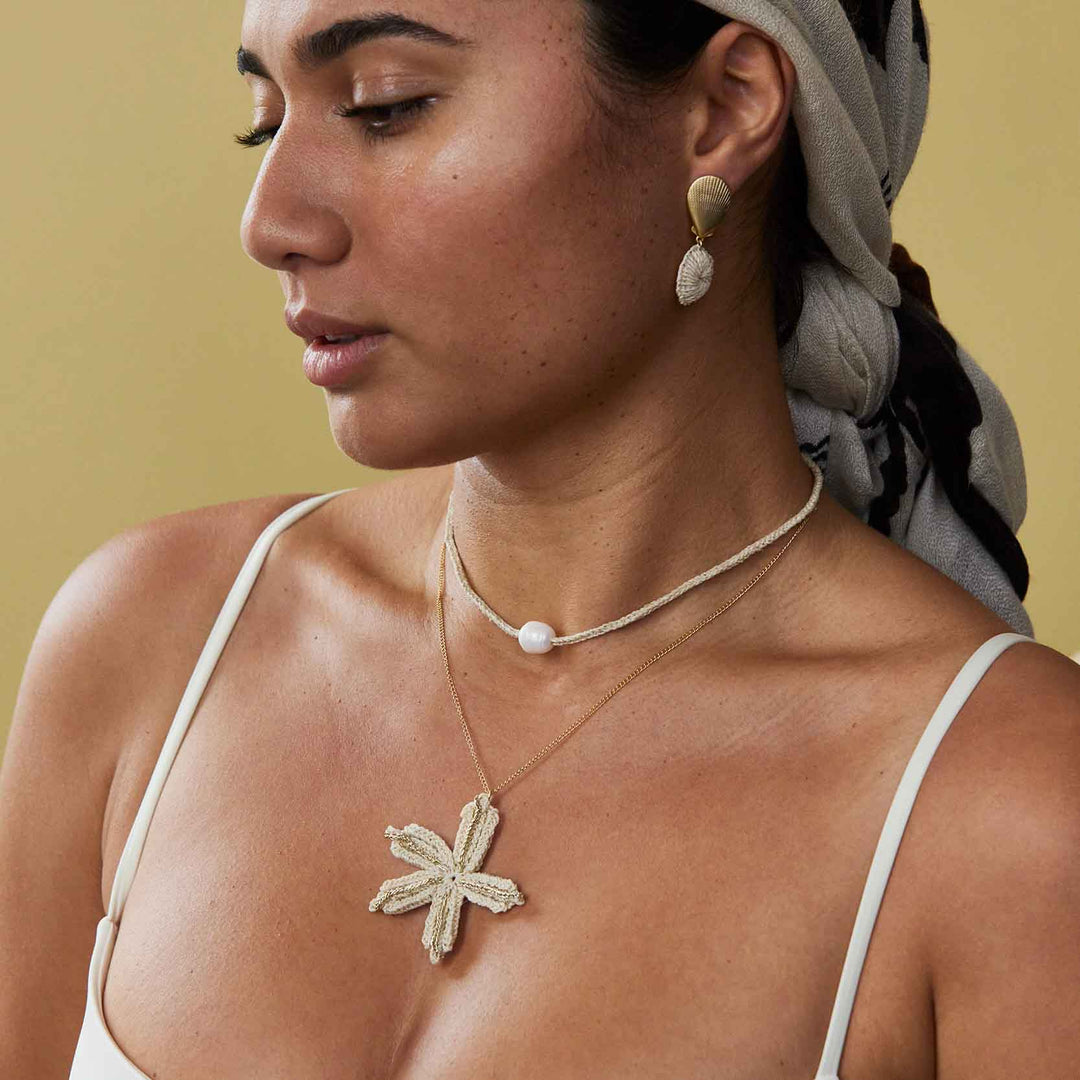 Woman wearing a necklace and earrings with a neutral background