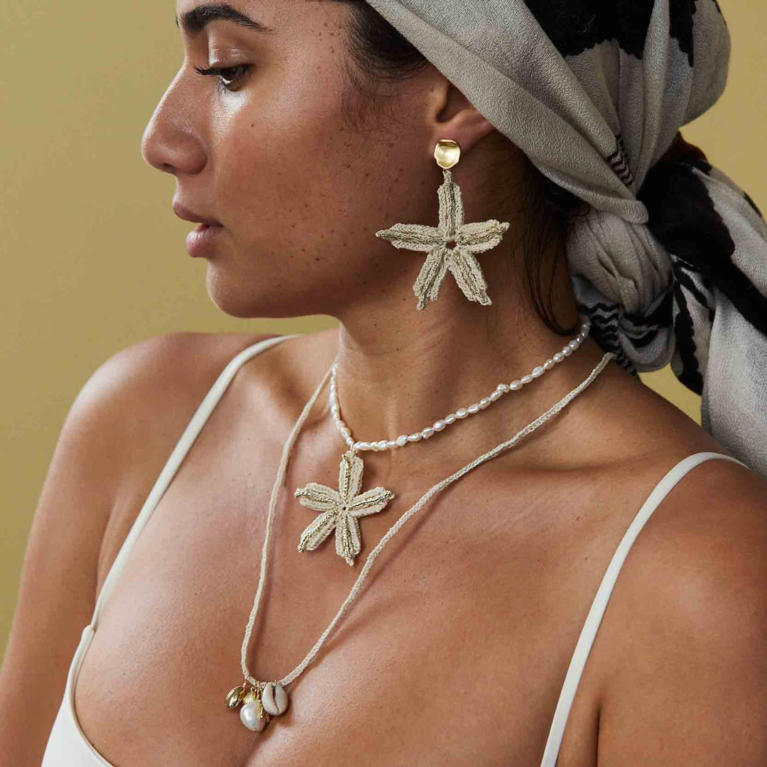 Woman wearing starfish-shaped earrings and necklace against a neutral background