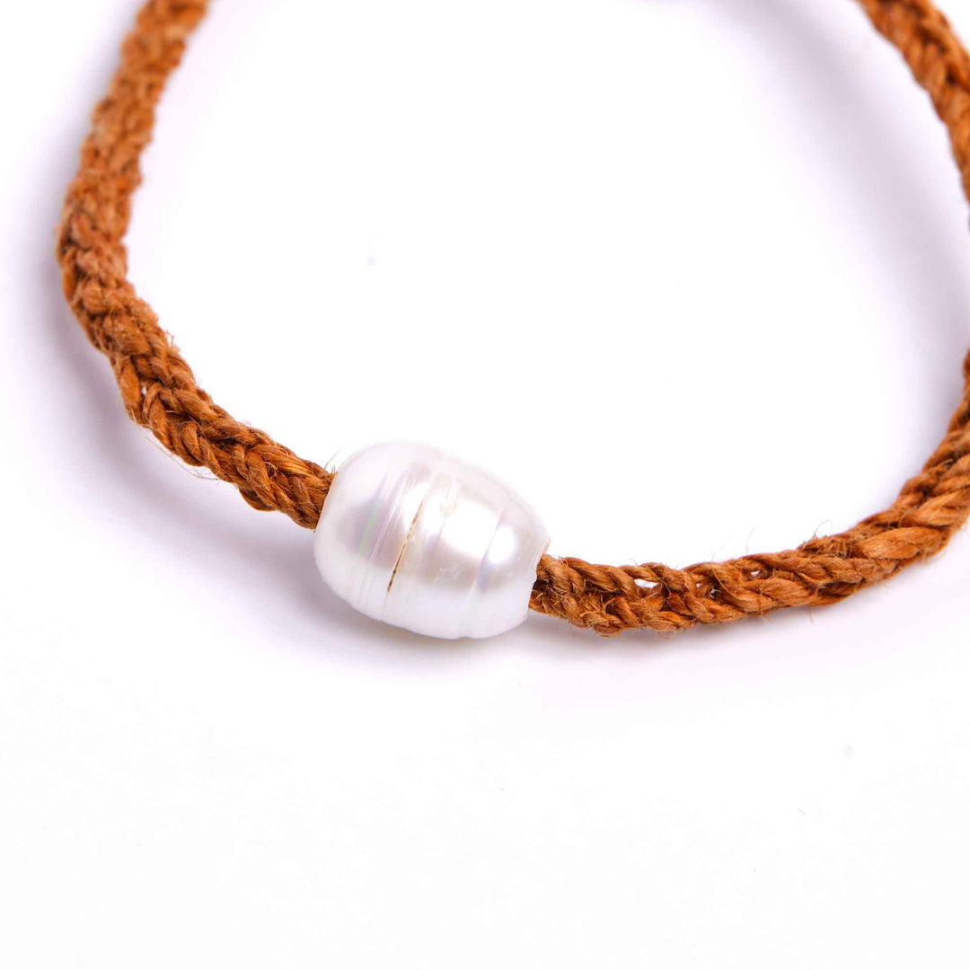 Brown braided bracelet with a pearl bead on a white background