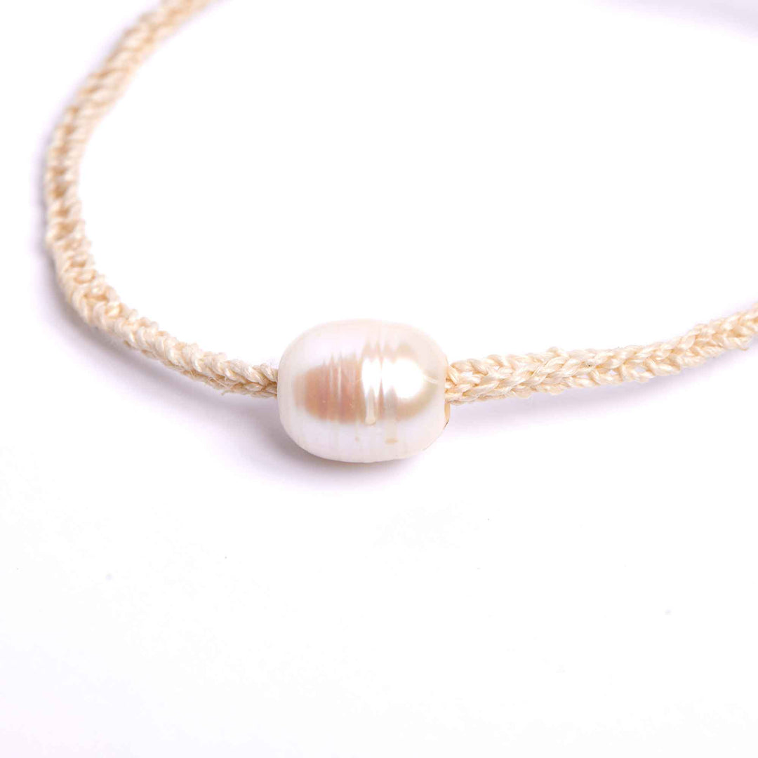 Pearl necklace with gold cord on a white background