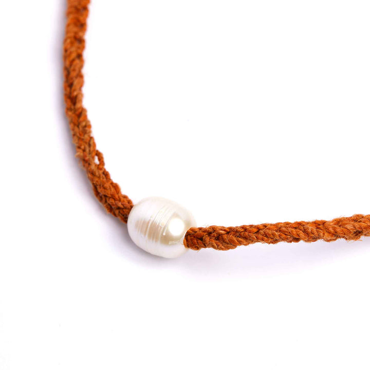 Necklace with orange cord and white pearl on a white background