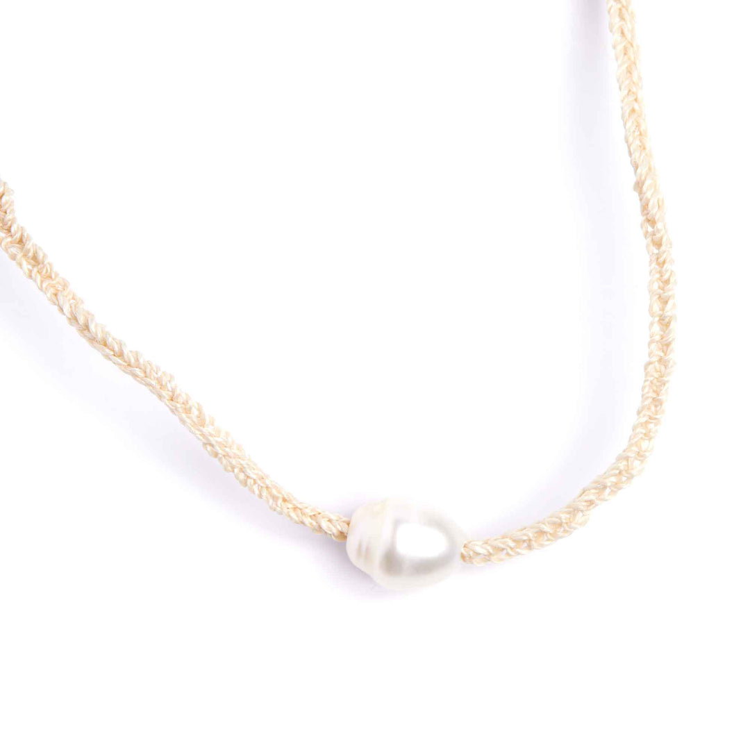 Gold necklace with a single pearl on a white background