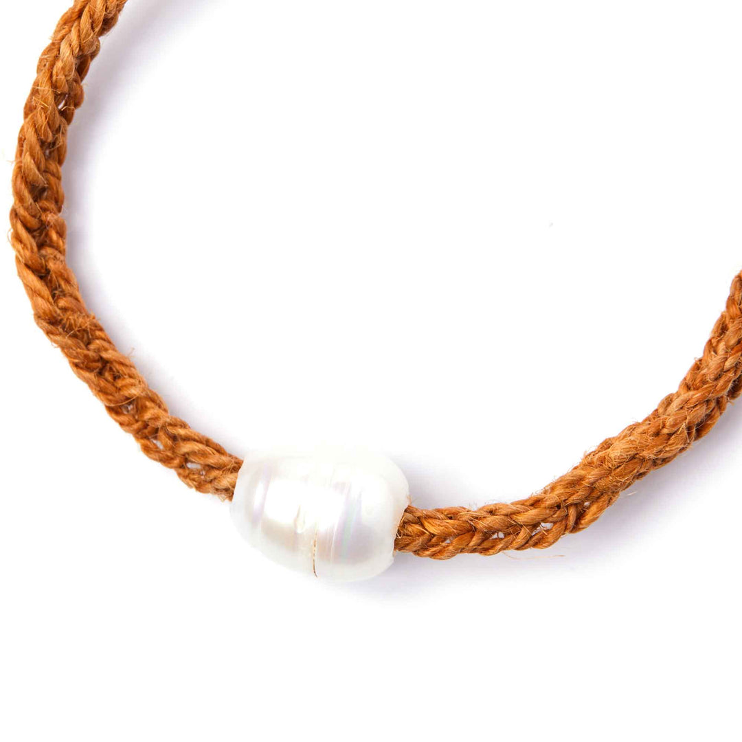 Necklace with braided brown cord and large white bead on a white background