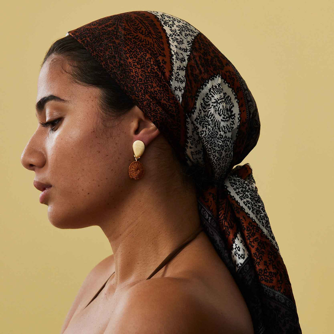 Woman wearing a patterned headscarf on a beige background