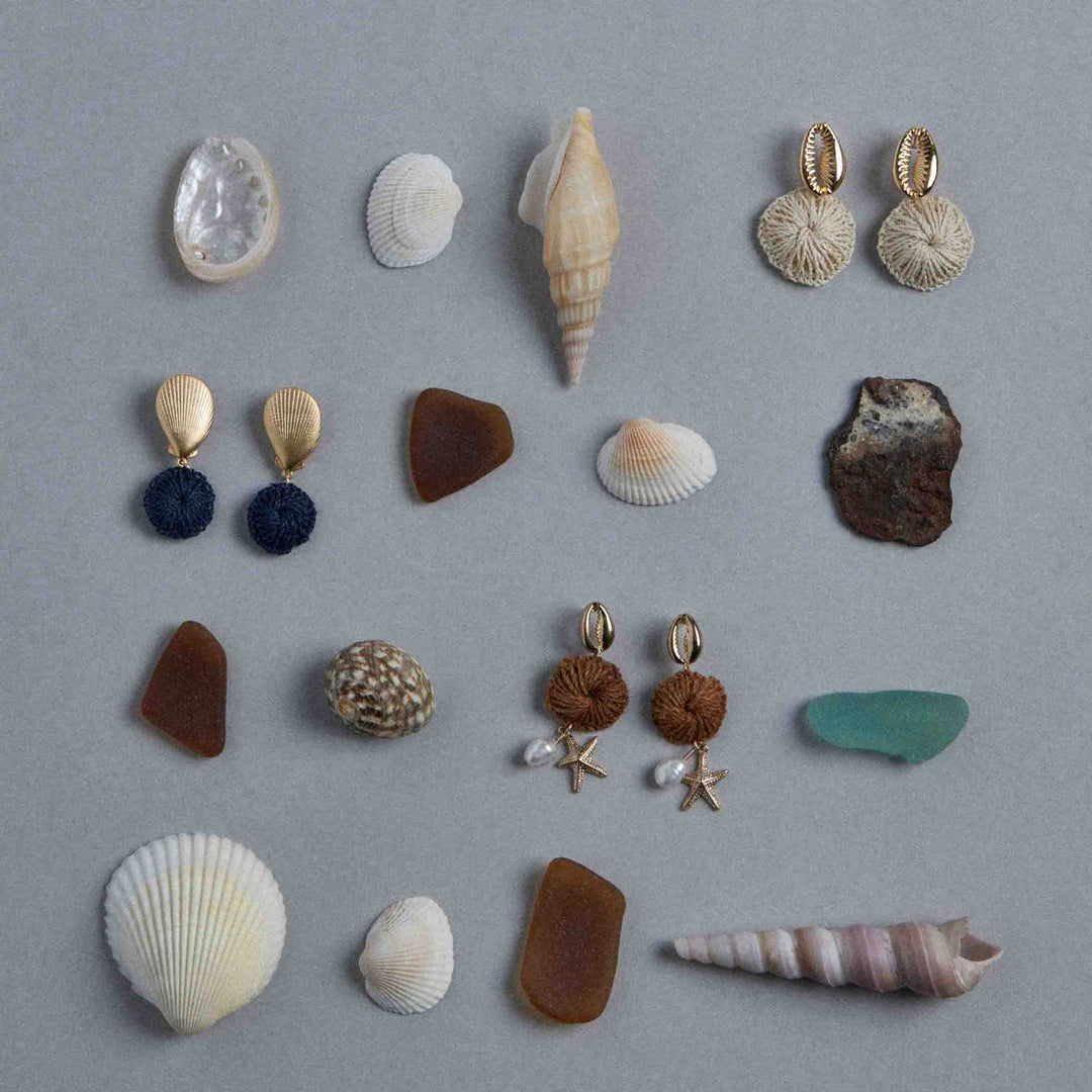 Collection of seashells and earrings on a gray background