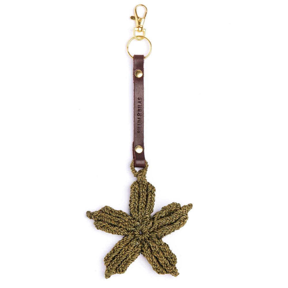 Green crocheted leaf-shaped keychain with brown leather strap on a white background