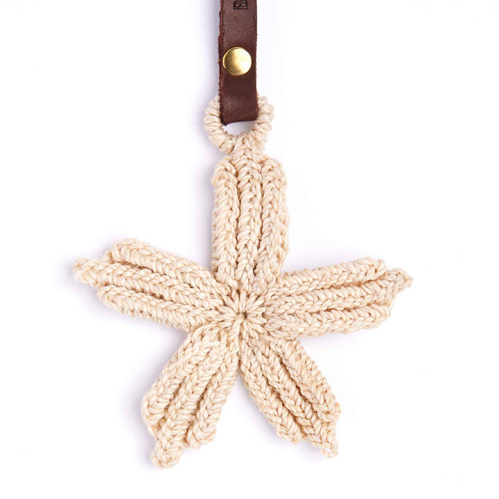 Crocheted starfish ornament with leather strap on a white background