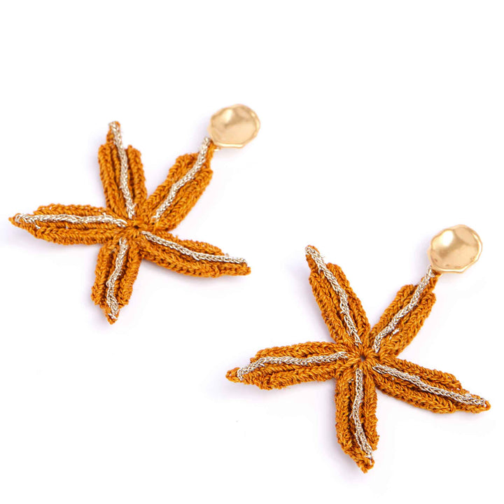Pair of orange starfish-shaped earrings on a white background