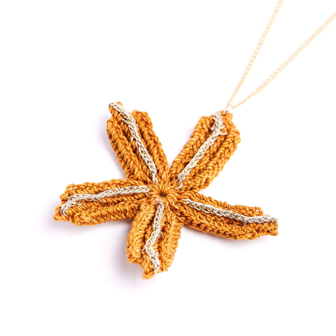 Knitted star-shaped ornament with white accents on a white background
