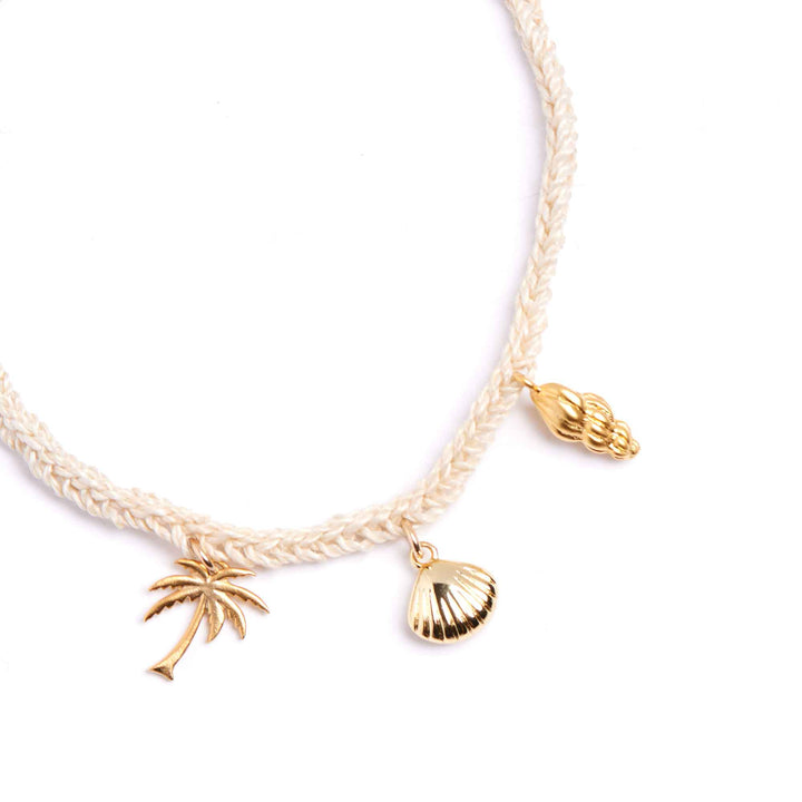 Gold anklets with palm tree and shell charms on a white background