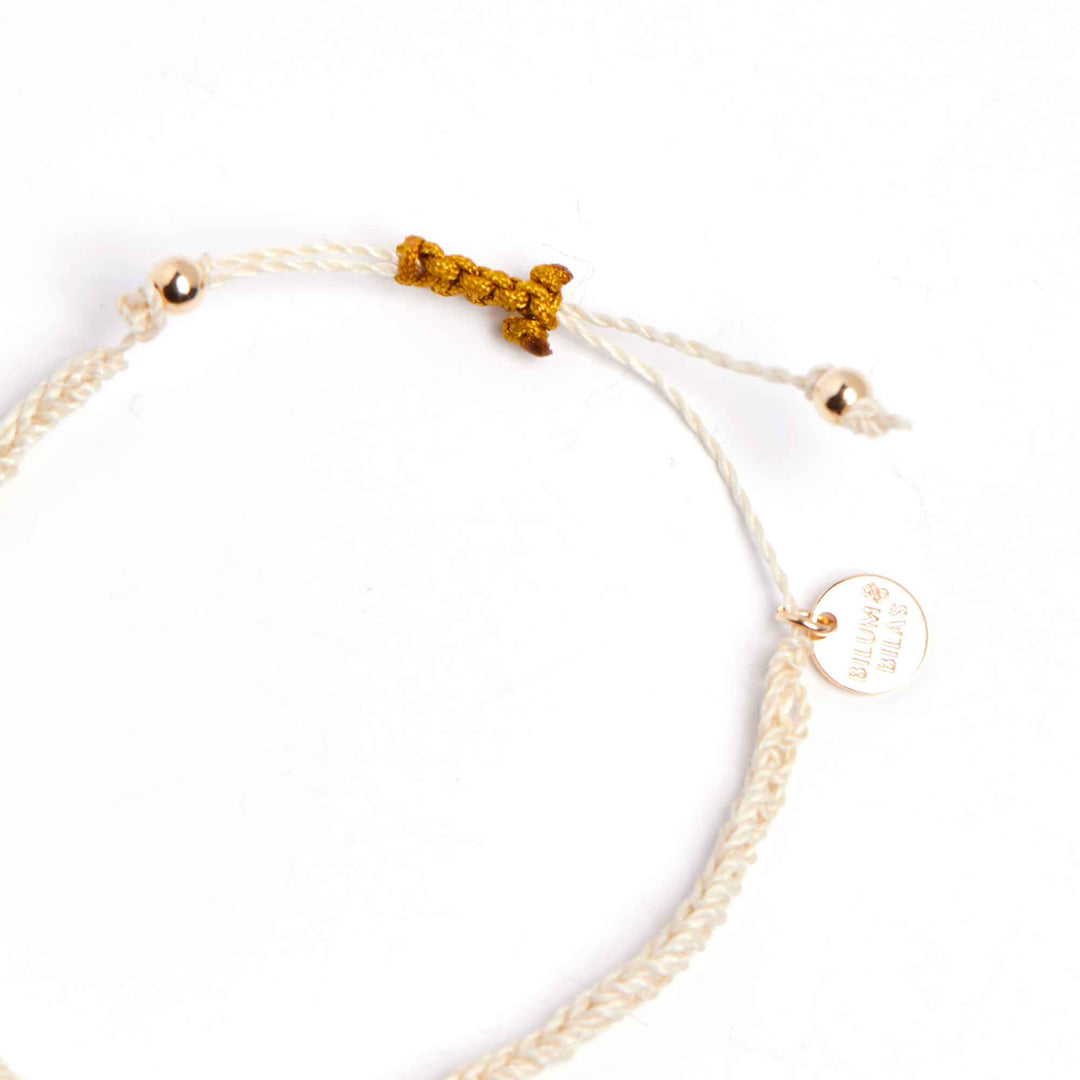 Gold bracelet with a small tag on a white background