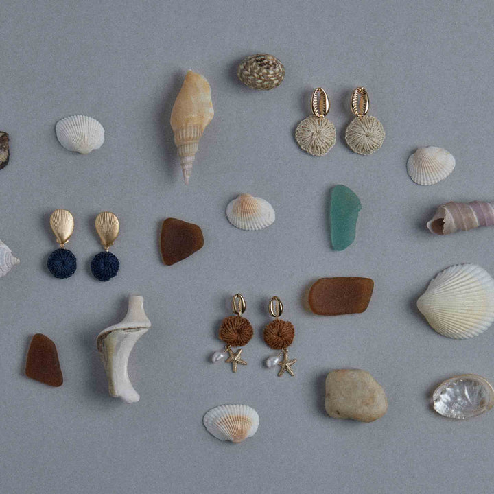 Collection of seashells, stones, and earrings on a gray background