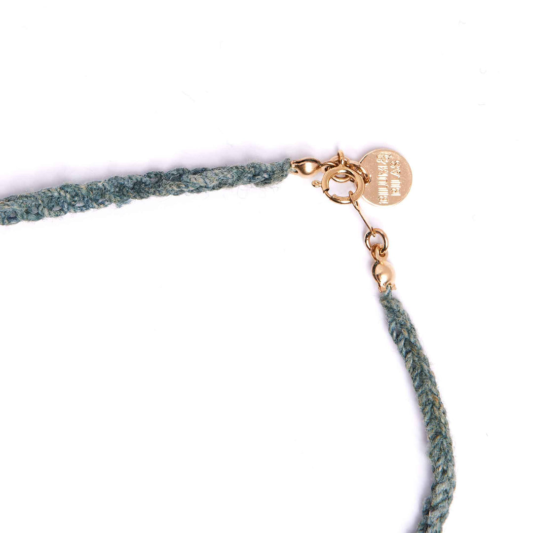 Green woven necklace with a gold clasp on a white background