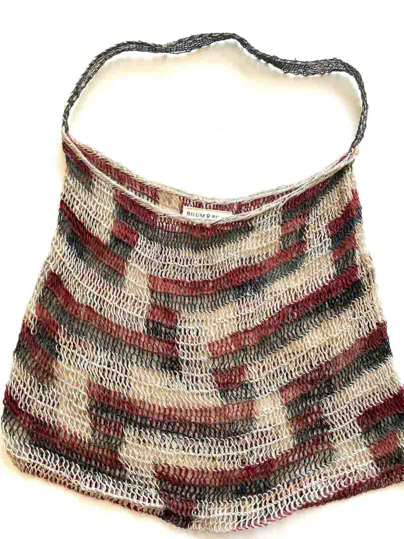 Flat lay of traditional brown and green tone string bilum bag from Moment Village in Papua New Guinea hanging.