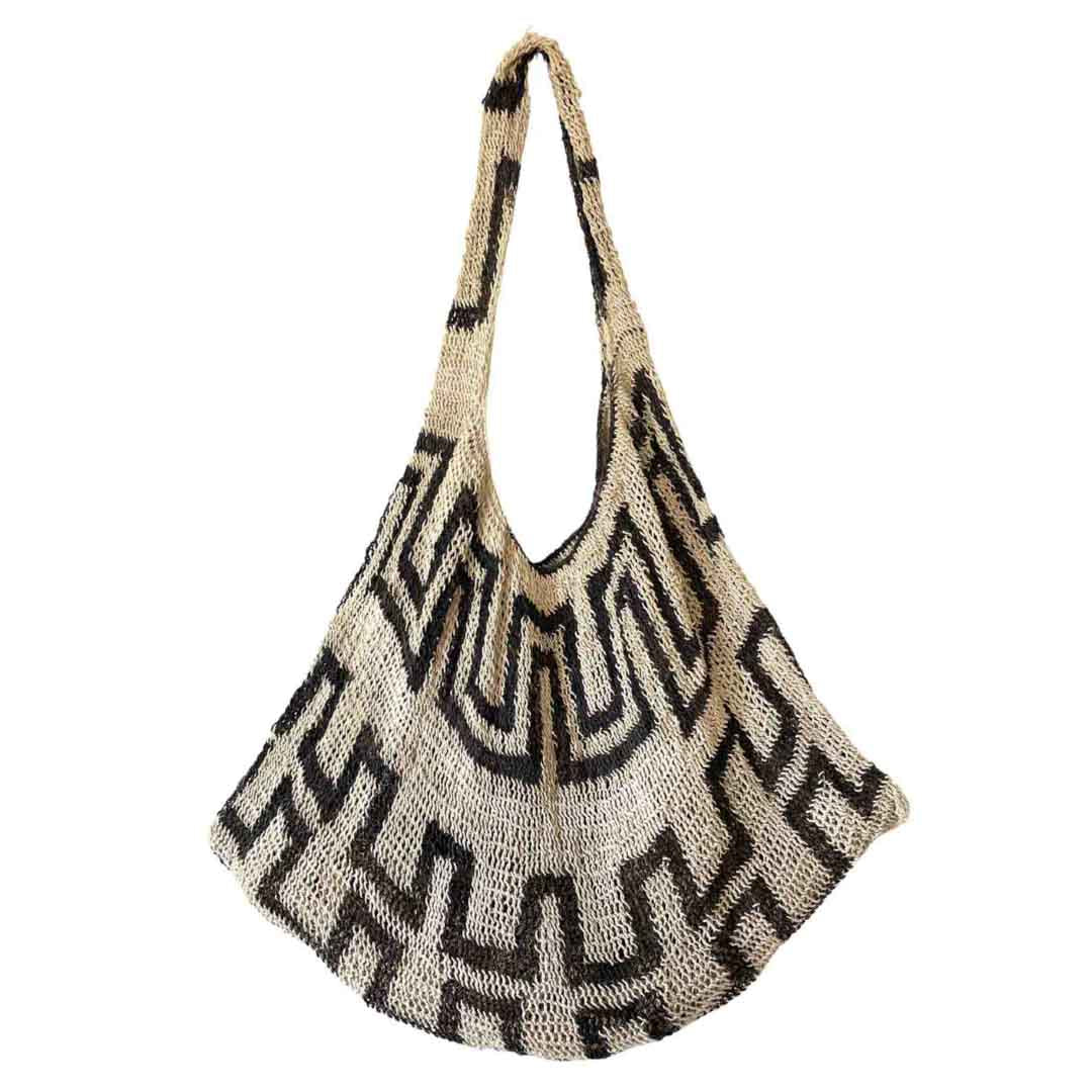 Black and white patterned natural fibre string bilum bag from Papua New Guinea hanging on white background.