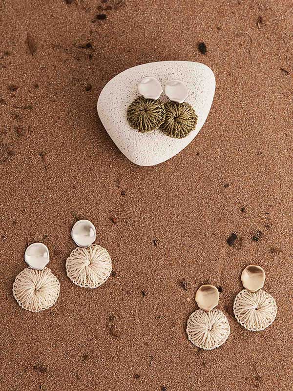 Collection of Bilum and Bilas warped gold and silver stud earrings with a dangling handwoven natural fibre disc on top of red sandstone