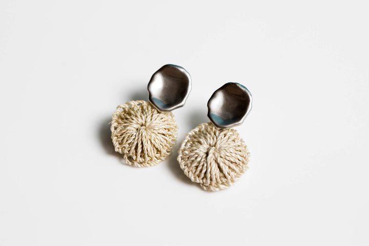 Bilum and Bilas warped silver stud earring with a dangling handwoven natural fibre disc side angle