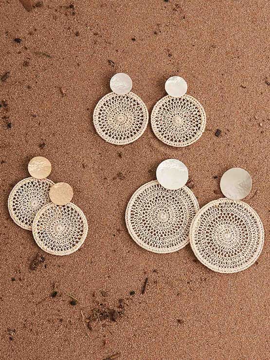 Collection of handwoven natural fibre boho chic Bilum and Bilas statement earrings on sandstone