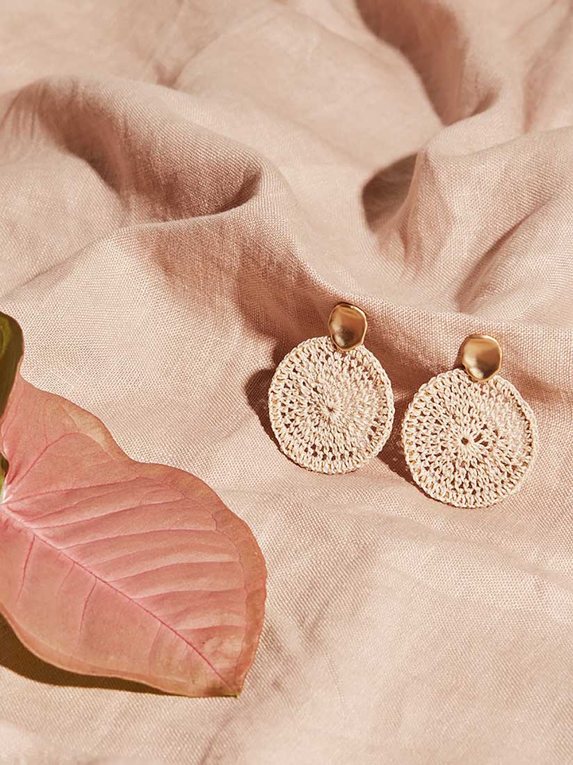 Bilum and Bilas Sowana disc earrings - Crochet woven disc earrings with gold ear post on pink linen with plant