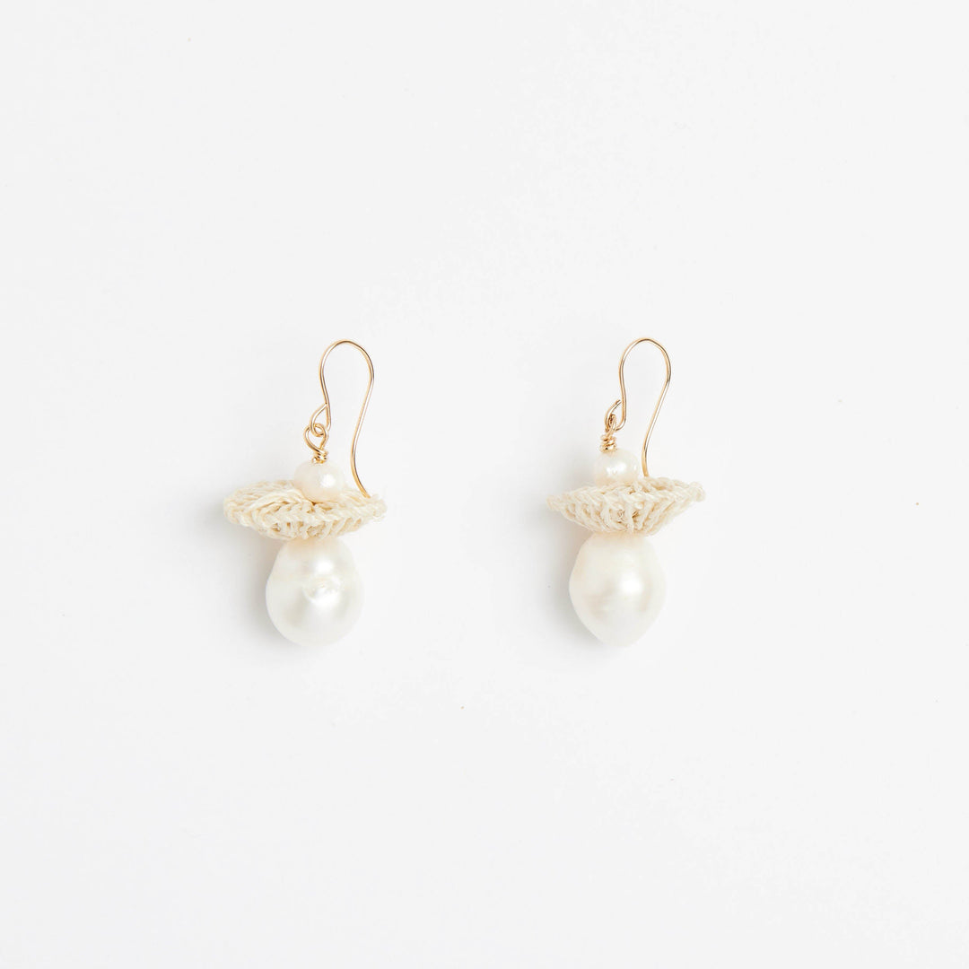 Front view of gold pearl drop earrings with woven natural fibre disc