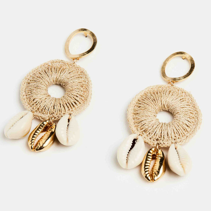 Dangle statement gold earring with handwoven hoop featuring natural and gold cowry shells on a side angle