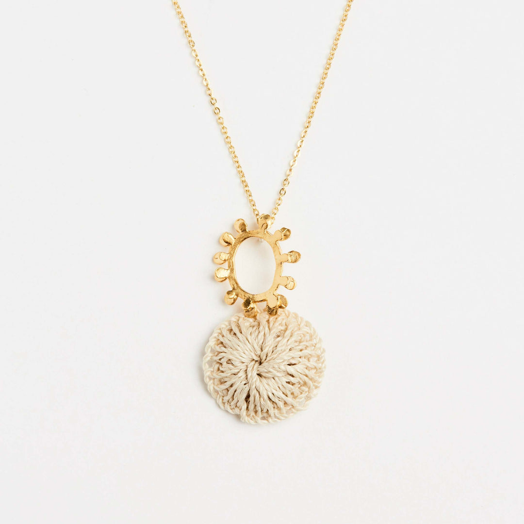 Close up of gold textured sun pendant with natural fibre woven disc on a gold filled chain necklace