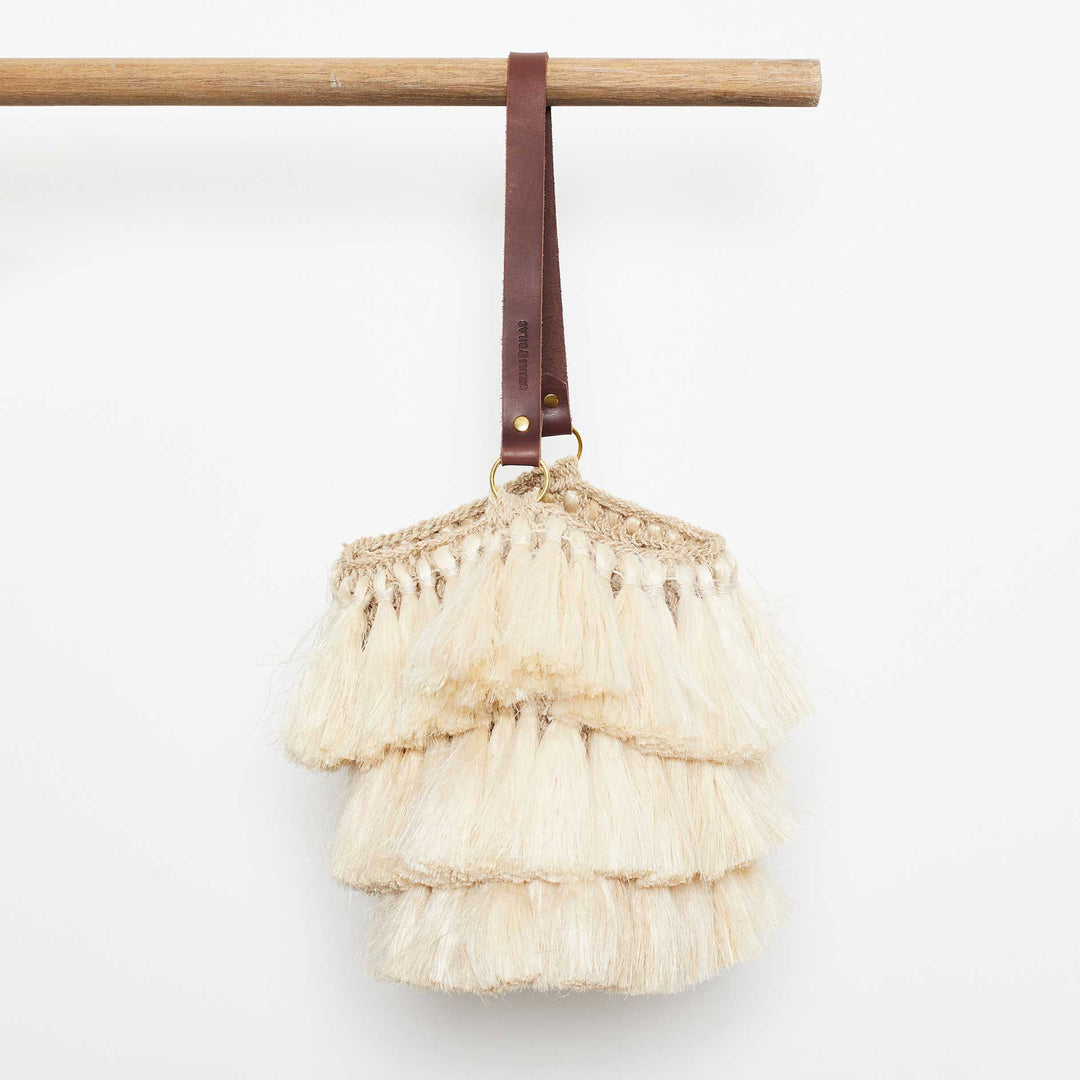 Three-tiered fringed handwoven bag on white background side profile
