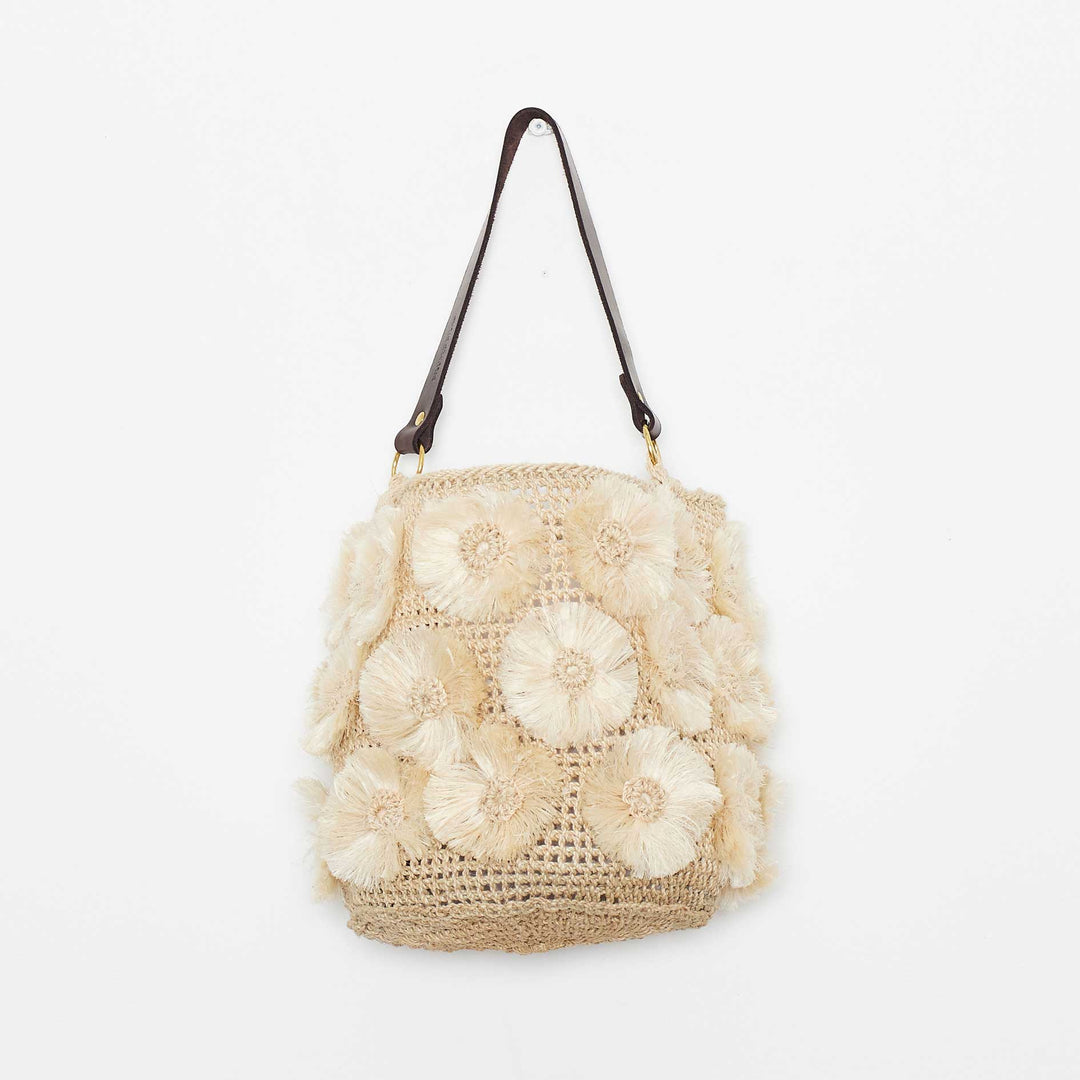 Handwoven natural bag with handmade flower details on white background.